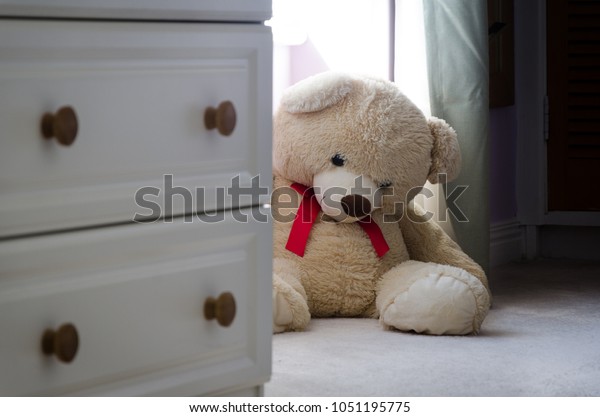 Teddy Bear Peeping Around Bedroom Furniture Stock Photo