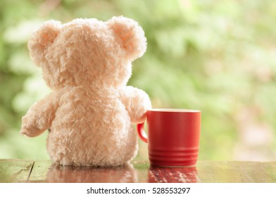 Teddy bear relaxes with coffee in red cup and sees nature background, Chill out concept