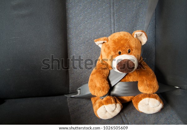 Teddy Bear with safety belt in a car in driving\
safe concept.
