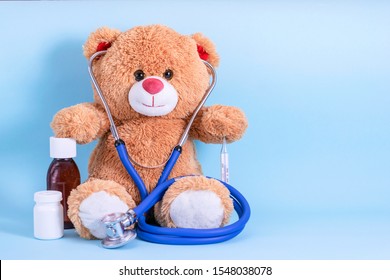 Teddy bear, stethoscope, thermometer, pills and cough syrup on blue background with space to copy; fun Pediatrics concept; children's medicine