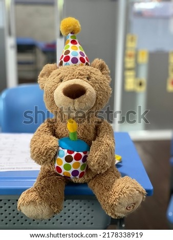 Teddy bear wearing birthday hat and holding a birthday cake