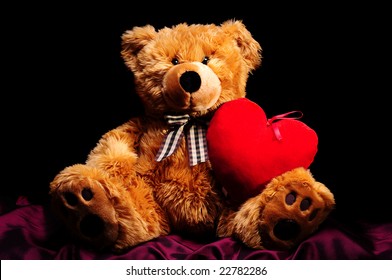 A teddy-bear with big red heart on black background