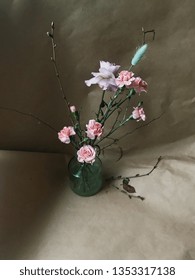 Teder composition with fresh rose, spring twigs, ear and pink carnation flowers. Spring bouquet in glass vase on the brown craft background 