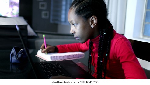 Teen African Girl Doing Homework At Night, Black Adolescent Female Writing Note In Front Of Computer