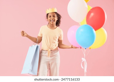 Teen African-American girl with shopping bags, balloons and crown on pink background. Birthday celebration - Powered by Shutterstock