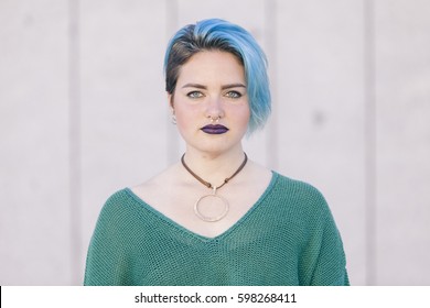 Teen Androgynous Woman With Sad Expression And Blue Dyed Hair Isolated On The Street Wearing A Nose Piercing