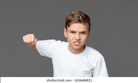 Teen Anger. Furious Teenager Punching At Camera With Angry Facial Expression, Grey Studio Background