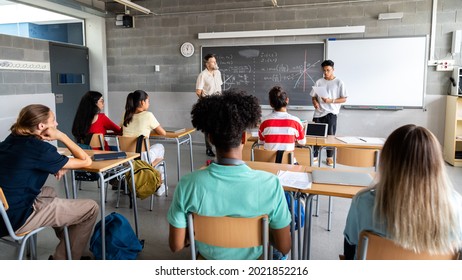 Teen asian boy high school student giving a presentation in class to his multiracial classmates and male teacher. Horizontal banner image.