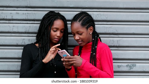 Teen black girls using cellphone, adolescent girlfriends laughing and smiling on social media