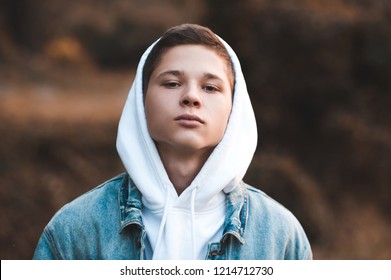 Teen boy 16-17 year old wearing white hoodie and denim jacket closeup. Looking at camera. 20s. 