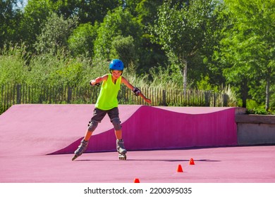 Teen Boy In Blue Helmet Skate Fast On Rollerblades In The Skatepark Wearing Protection And Going Around Cones