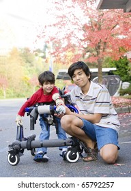 Teen Boy With Disabled Little Brother In Walker Out Walking