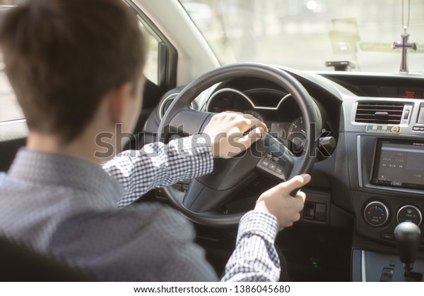 teen boy driving a car view from the\
car .teen holding hands behind the wheel of the\
car\
