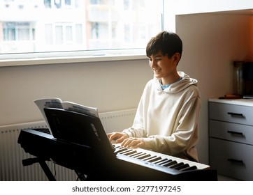 Teen boy enjoy playing practicing electronic piano keyboard in his free time in his room at home. Healthy living life style concept. - Powered by Shutterstock