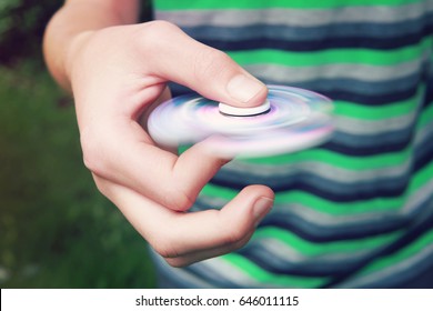 Teen boy with a fidget spinner outdoors