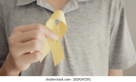Teen Boy Hand Holding Yellow Gold Ribbon, Sarcoma Awareness, Bone Cancer, Childhood Cancer Awareness, World Suicide Prevention Day, September Yellow