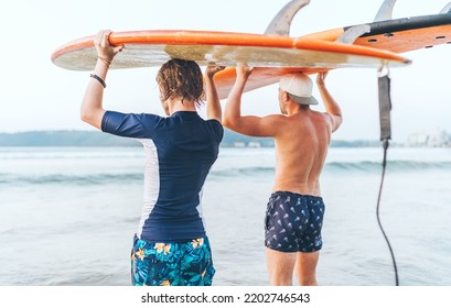 Teen boy with his father with surfboards on the heads walking in the waves on Udawalawe beach in Sri Lanka. Family active vacation or active sporty people concept. - Powered by Shutterstock