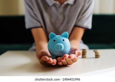 Teen Boy Holding Blue Piggy Bank. Kids Financial Education And Responsibility, Accumulation And Savings Planning. The Child Manages And Deposits His Finance, Investment Concept.