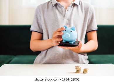 Teen Boy Holding Blue Piggy Bank. Kids Financial Education And Responsibility, Accumulation And Savings Planning. The Child Manages And Deposits His Finance, Investment Concept.