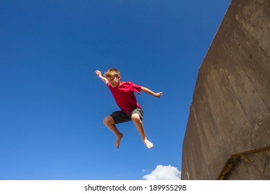 Teen Boy Jumping Blue Sky Teen Boy Jumping Off Wall Against Blue Sky Onto Beach Parkour