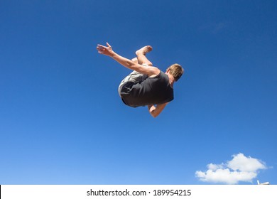 Teen Boy Jumping Somersaults Teen Boy Jumping Off Wall Into Somersaults Flips Into Blue Sky On Beach In Parkour