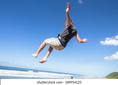 Teen Boy Jumping Somersaults Parkour Teen Boy Jumping Off Wall Into Somersaults Flips Into Blue Sky On Beach In Parkour