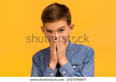 Teen boy with look of disgust pinching his nose to avoid bad smell, teenage male kid capturing strong reaction to unpleasant odor, his face twisted in grimace, isolated on yellow studio background