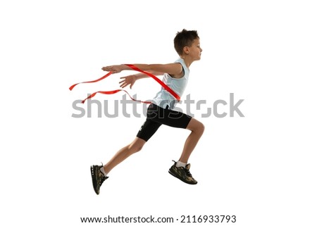 Teen boy in motion, running athlete crossing winning red ribbon isolated over white background. Concept of action, sport, healthy life, competition, motion, physical activity. Copy space for ad