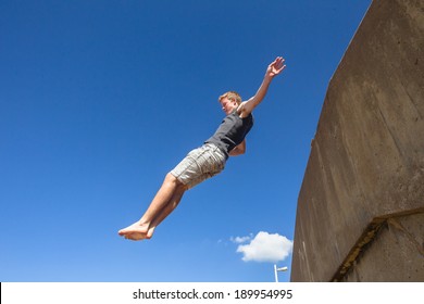 Teen Boy Parkour Jumping Blue Sky Teen Boy Parkour Jumping Off Wall Against Blue Sky Onto Beach