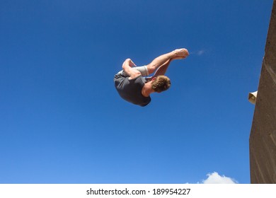 Teen Boy Parkour Jumping Somersaults Teen Boy Parkour  Jumping Off Wall Into Somersaults Flips Into Blue Sky On Beach