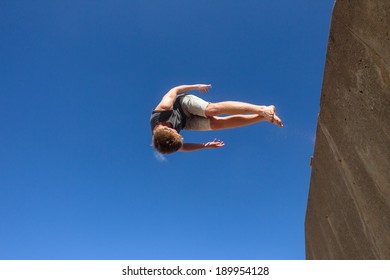 Teen Boy Parkour Somersaults Teen Boy Parkour Jumping Off Wall Into Somersaults Flips Into Blue Sky On Beach