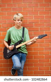 Teen Boy Playing Guitar Outdoors