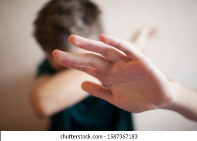 Teen boy protects himself with his hand, his face is out of focus