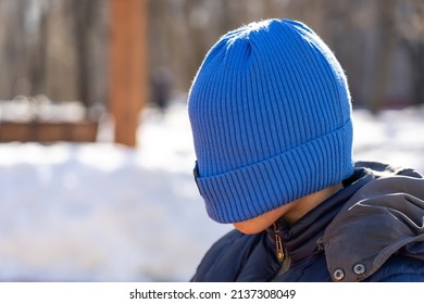 Teen boy pulled blue knitted hat over his eyes to hide his face from the camera lens, family lifestyle