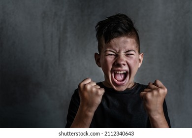 Teen boy screaming in anger on dark background. The problem of helping teenagers in a difficult period 