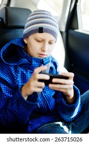 Teen Boy Sitting In The Car With Phone