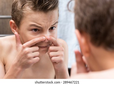 Teen boy touching his nose. Squeezing pimple. 