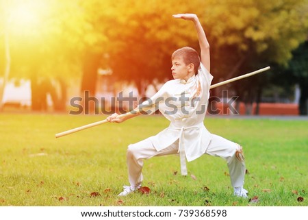 teen boy trains in kimono wushu outdoor