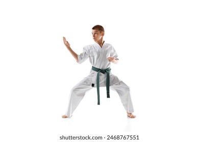 Teen boy in white karate and green belt demonstrating skills in stance, practicing isolated on white studio background. Concept of sport, martial arts, combat sport, healthy and active lifestyle - Powered by Shutterstock