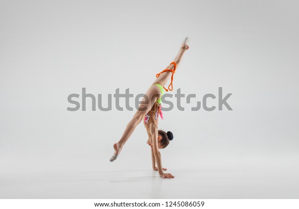 The teen\
female little girl doing gymnastics exercises with jump rope\
isolated on a gray studio background. The gymnastic, stretch,\
fitness, lifestyle, training, sport\
concept