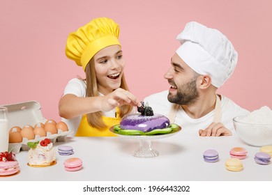 Teen fun girl dad father chef cook confectioner baker in yellow apron toque cap at table decorating pie with blackberry berry isolated on pink background Mousse cake food workshop master class process - Shutterstock ID 1966443202