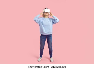 Teen gamer girl experiences fantasy world wearing virtual reality glasses with headphones. Full body studio shot female student in VR headset exploring educational videogame and learning about science - Powered by Shutterstock