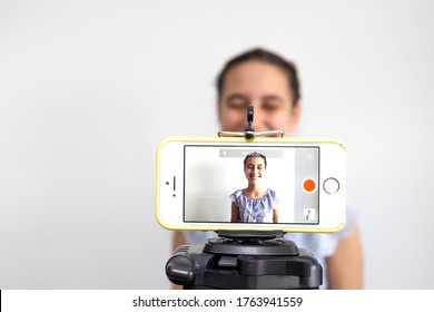 Teen Girl Blogger Influencer Recording Video Blog Concept Speaking Looking At Smartphone On Tripod At Home. Teenager Social Media Vlogger Shooting Vlog, Streaming Online Podcast On Mobile Phone