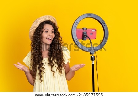 Teen girl blogger influencer use selfie led lamp and smartphone on tripod for making online video tutorial. Teenager vlogger making vlog for kids channel. Positive and smiling emotions of teen girl.