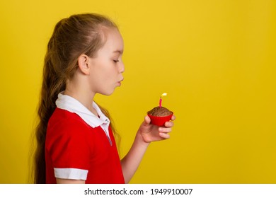 Teen girl blows out a candle on a cupcake and makes a wish. Happy birthday or make a wish concept. Banner with copy space.