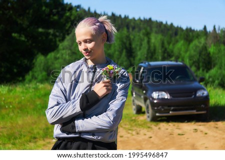 teen girl with a bouquet of wildflowers in nature on the background of the car