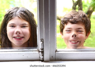 Teen Girl  And Boy Siblings With Nose Pressed Against The Window Close Up Portrait