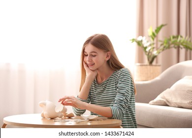 Teen Girl With Broken Piggy Bank And Money At Home