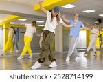 Teen girl in cap rehearses modern dances in dance hall