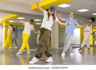 Teen girl in cap rehearses modern dances in dance hall - Powered by Shutterstock